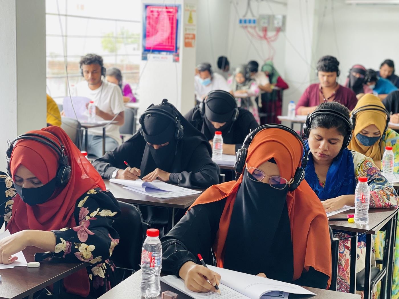 Students wearing headphones during a paper-based IELTS listening practice
